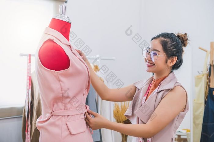 快乐亚洲女时尚设计师女孩使适合的正式的衣服统一的衣服人体模型模型时尚设计师时尚的展厅缝纫和裁缝概念有创意的裁缝设计师