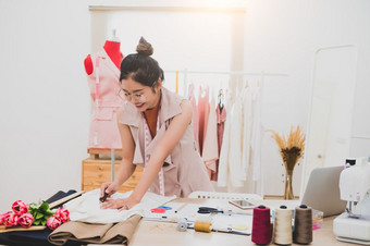 有吸引力的亚洲女时尚设计师工作首页办公室车间时尚的时尚达人女人创建新布设计集合裁缝和缝纫人生活方式和占领概念