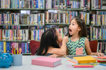 两个小快乐可爱的女孩使有趣的脸和玩在一起图书馆学校牙科健康检查教育和自<strong>我学</strong>习无线技术人生活方式和友谊