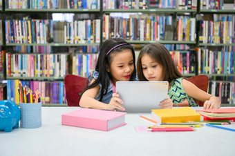 两个小快乐可爱的女孩玩平板电脑计算设备图书馆学校教育和自<strong>我学</strong>习无线技术概念人生活方式和友谊学前教育孩子们