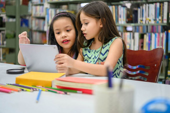 两个小快乐可爱的女孩玩平板电脑计算设备图书馆学校教育和自我学习无线技术概念人生活方式和友谊学前教育孩子们
