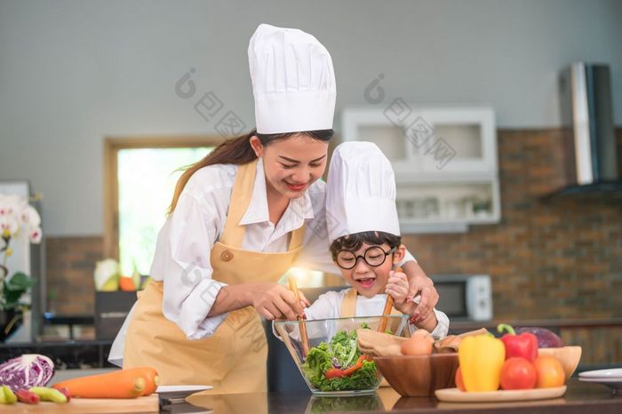 快乐美丽的亚洲女人和可爱的小男孩与眼镜准备烹饪厨房首页人生活方式和家庭自制的食物和成分概念两个泰国人生活