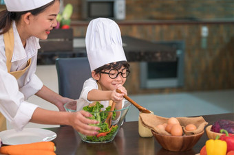快乐美丽的亚洲女人和可爱的小男孩与眼镜准备烹饪厨房首页人生活方式和家庭自制的食物和成分概念两个泰国人生活