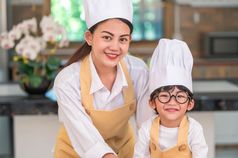 肖像美丽的亚洲女人和可爱的小男孩与眼镜准备烹饪厨房首页人生活方式和家庭自制的食物和成分两个泰国人看相机