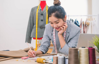 有吸引力的亚洲女时尚设计师工作首页办公室车间时尚的时尚达人女人创建新布设计集合裁剪和缝纫人生活方式和占领概念