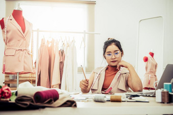 有吸引力的亚洲女时尚设计师工作首页办公室车间时尚的时尚达人女人创建新布设计集合裁缝和缝纫人生活方式和占领概念