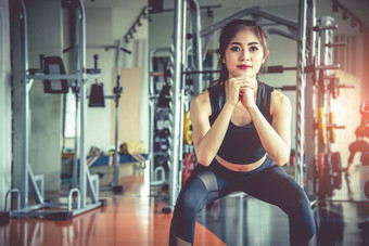 年轻的亚洲女人做蹲锻炼为脂肪燃烧和饮食健身体育健身房与体育设备背景美和身体构建概念体育俱乐部和有氧主题