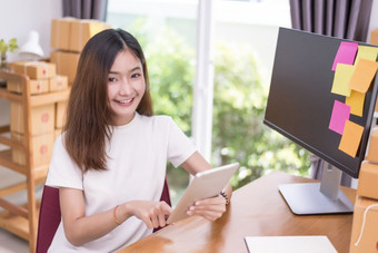 亚洲女人使用平板电脑与包裹盒子交付服务主题部分时间和生活方式概念