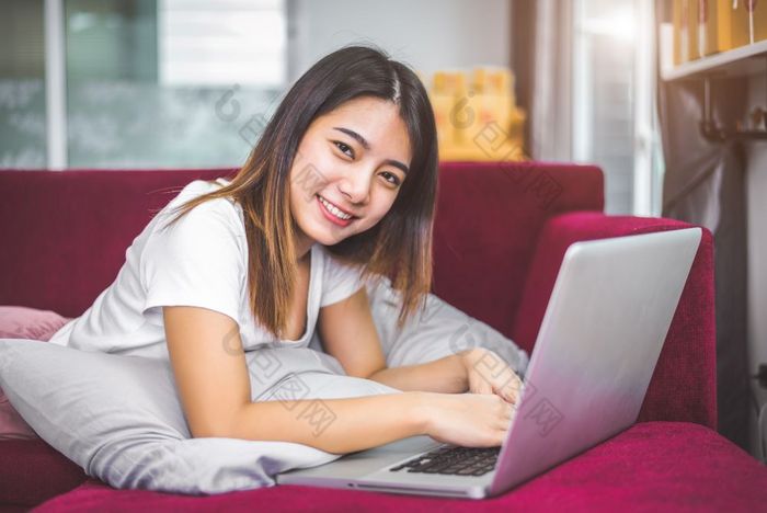 年轻的女人冲浪的互联网移动PC红色的沙发快乐的手势情绪情感销售和在线购物概念商人和市场营销幸福新业务交易员和企业家