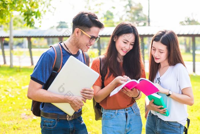 三个亚洲年轻的校园学生享受辅导和阅读书在一起友谊和教育概念校园学校和大学主题幸福和有趣的学习大学