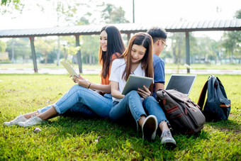 集团亚洲大学学生使用平板电脑和移动PC草场在户外技术和教育学习概念未来技术和现代娱乐概念象娱乐一样主题