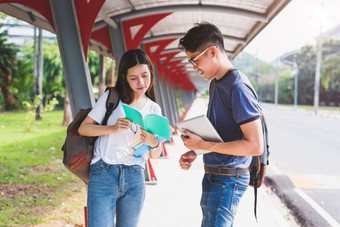 两个亚洲年轻的大学人讨论关于阅读书和使用移动PC为搜索和学习知识教育和友谊概念幸福和学习概念情人和朋友主题