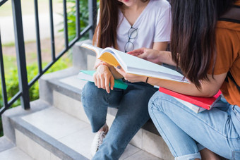 关闭两个亚洲美女孩阅读和辅导书为最后检查在一起学生微笑和坐着楼梯教育和回来学校概念生活方式和人主题