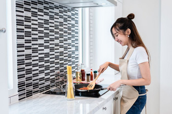 亚洲女人烹饪意大利面厨房幸福的人和生活方式概念食物和喝主题室内装饰和做家务主题