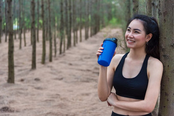 美亚洲体育运动女人休息和持有喝水瓶和放松中间森林后累了从慢跑女孩看吸引力视图锻炼概念生活方式主题