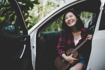 美亚洲女人<strong>微</strong>笑和有有趣的在户外夏天与尤克里里琴白色车旅行摄影师概念赶时髦的人风格和只有女人<strong>主题</strong>生活方式和幸福生活<strong>主题</strong>