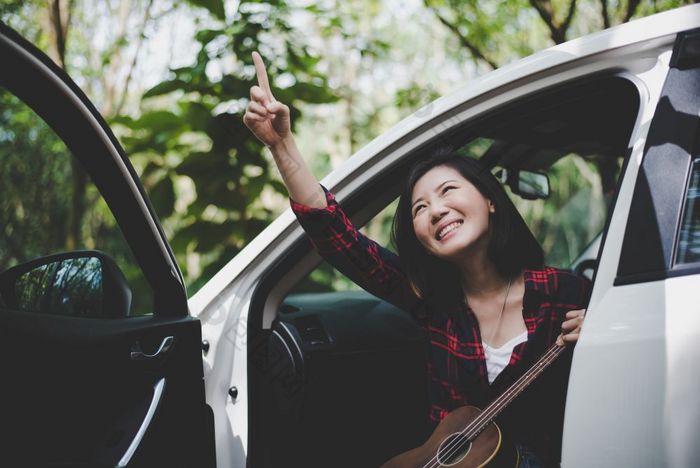 美亚洲女人指出和有有趣的在户外夏天与尤克里里琴白色车旅行摄影师概念赶时髦的人风格和只有女人主题生活方式和幸福生活主题