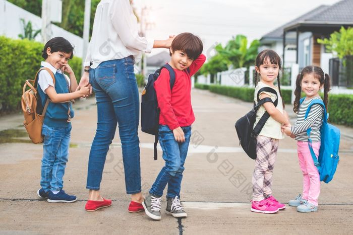 回来学校学生妈妈。集团会学校在一起父发送小男孩和女孩为第一个类学期术语与书包书包在一起协作学习和同理心托儿所