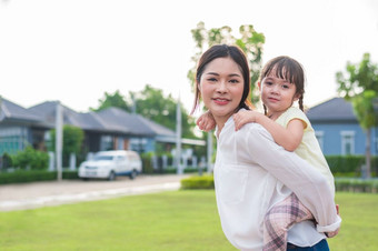 小女孩骑回来与她的妈妈人和生活方式概念快乐家庭和首页甜蜜的首页主题操场上和在户外公园主题