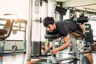 亚洲体育运动男人。伸展运动和提升重量两个腿当面对下来为伸展运动肌肉健身健身房公寓背景体育运动和人生活方式概念腿旋度的姿势