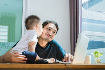儿子接吻他的父亲而使用互联网人和生活方式概念技术和快乐家庭主题单爸爸主题