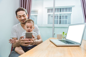 亚洲父亲和儿子使用聪明的电话在一起首页背景技术和人概念生活方式和快乐家庭<strong>主题</strong>互联网和沟通<strong>主题</strong>