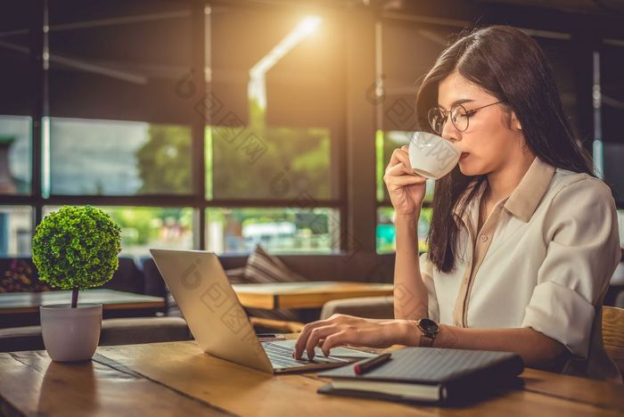 亚洲工作女人使用移动PC和喝咖啡咖啡馆人和生活方式概念技术和业务主题自由和占领主题工作狂在一夜之间概念
