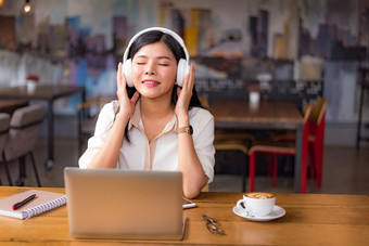 美丽的亚洲女人放松和听音乐咖啡馆与移动PC电脑和咖啡杯人和生活方式概念自由快乐工作场所主题大学和大学主题