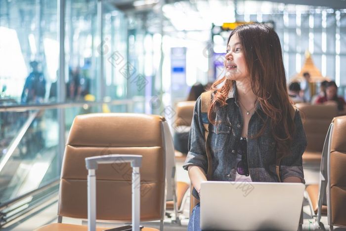 美亚洲女人使用移动PC和看外机场女人坐着机场终端人和生活方式概念技术和旅行主题业务和肖像主题