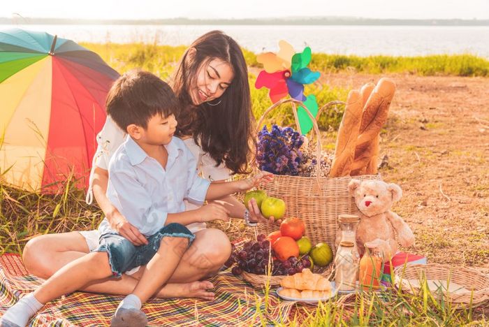 美丽的亚洲妈妈。和儿子做野餐和复活节夏天聚会，派对草地附近湖和山假期和假期人生活方式和快乐家庭生活概念泰国人