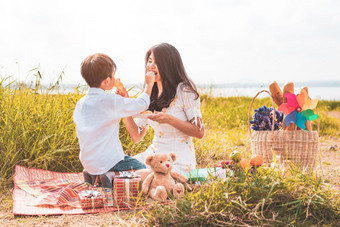 小亚洲男孩他的<strong>妈妈喂</strong>养零食每一个其他草地当做野餐<strong>妈妈</strong>。和儿子玩在一起庆祝<strong>妈妈</strong>。一天和欣赏概念夏天人和生活方式主题