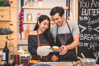 年轻的夫妻使面包店甜甜圈和面包面包店商店业务所有权企业家丈夫和妻子烹饪在一起厨房幸福人和生活方式的关系概念
