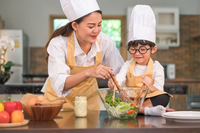 快乐美丽的亚洲女人和可爱的小男孩与眼镜准备烹饪厨房首页人生活方式和家庭自制的食物和成分概念两个泰国人生活