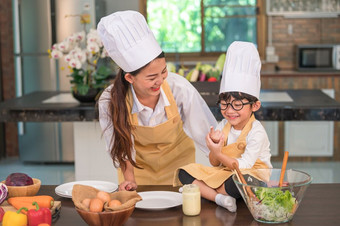 快乐美丽的亚洲女人和可爱的小男孩与眼镜准备烹饪厨房首页有趣的人生活方式和家庭自制的食物和成分概念两个泰国人生活