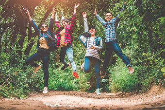 集团快乐亚洲十几岁的冒险旅行者拖拉机集团跳在一起山户外森林背景年轻的徒步旅行者朋友支持每一个其他人生存团队旅行和成功