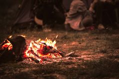 引发篝火与旅游人坐周围明亮的篝火附近野营帐篷森林夏天晚上背景集团学生户外火燃料旅行活动和长假期周末