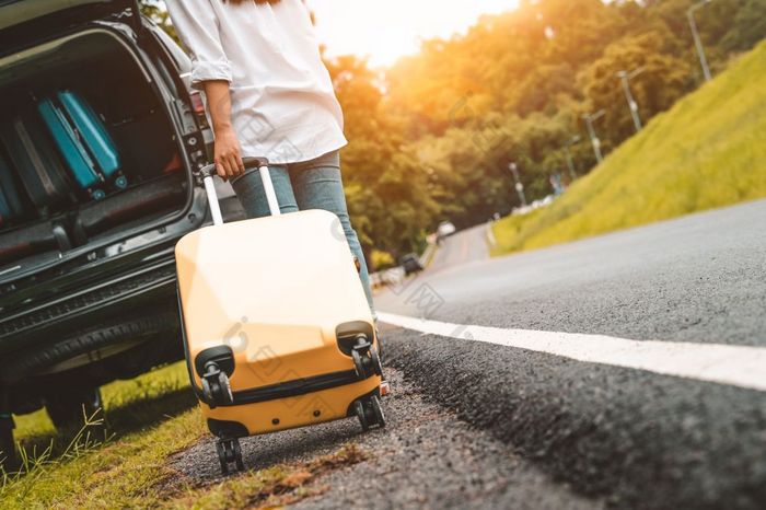 回来视图黄色的手提箱拖行李手提箱独自一人路旅行为加载成运动型多功能车车人生活方式和假期概念自然和夏天主题女孩有冒险运输