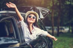 快乐女人挥舞着手外开放窗口车与草地和山森林背景人生活方式放松旅行者路旅行假期假期运输和周末旅行