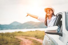 快乐女人挥舞着手外开放窗口车与草地和山湖背景人生活方式放松旅行者路旅行假期假期运输和旅行概念
