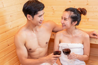 亚洲<strong>夫妻</strong>敬酒和喝酒桑拿房间为庆祝婚礼周年纪念日健康的皮肤热治疗与蒸汽桑拿概念假期和放松皮奥普克<strong>生活方式</strong>在一起