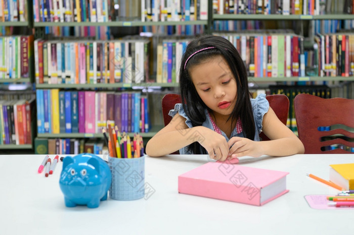 亚洲女孩折叠和制作纸图书馆在艺术类教育和活动概念