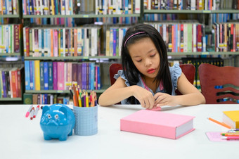 亚洲女孩折叠和制作纸图书馆在艺术类教育和活动概念