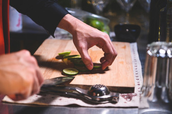 特写镜头专业酒保手切片柠檬为使柠檬水汁刀晚上俱乐部老板使饮料为客人酒吧餐厅食物和饮料概念