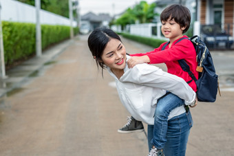 单妈妈携带和玩与她的孩子们附近首页与别墅街背景人和生活方式概念快乐家庭和首页甜蜜的首页主题在户外和自然主题