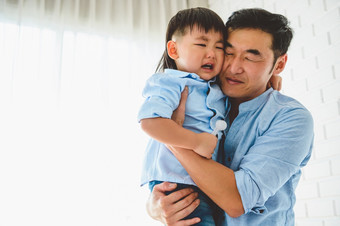 亚洲日本父亲携带和安慰他的哭儿子卧室他的首页与窗口和白色窗帘背景人生活方式健康检疫新冠病毒冠状病毒疫情