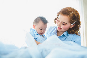 亚洲妈妈。和她的儿子穿蓝色的衬衫床上卧室与复制空间首页人生活方式和新生儿医疗概念状态检疫新冠病毒冠状病毒疫情主题