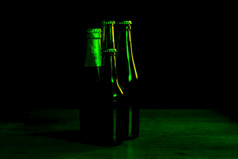 轮廓四个啤酒瓶黑色的背景与绿色灯那照亮他们一个一边轮廓四个啤酒瓶黑色的背景与绿色灯那照亮他们一个一边