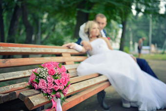 花束木板凳上与新娘和新郎的背景焦点的花花的背景的新婚夫妇花束木板凳上与新娘和新郎的背景焦点的花