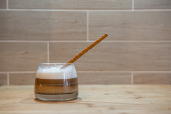 多层咖啡卡布奇诺咖啡玻璃杯木表格与面包稻草多层咖啡卡布奇诺咖啡玻璃杯与面包稻草