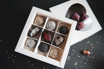 手工制作的糖免费的和谷蛋白免费的水果和巧克力糖果白色盒子和黑色的背景手工制作的水果和巧克力糖果白色盒子